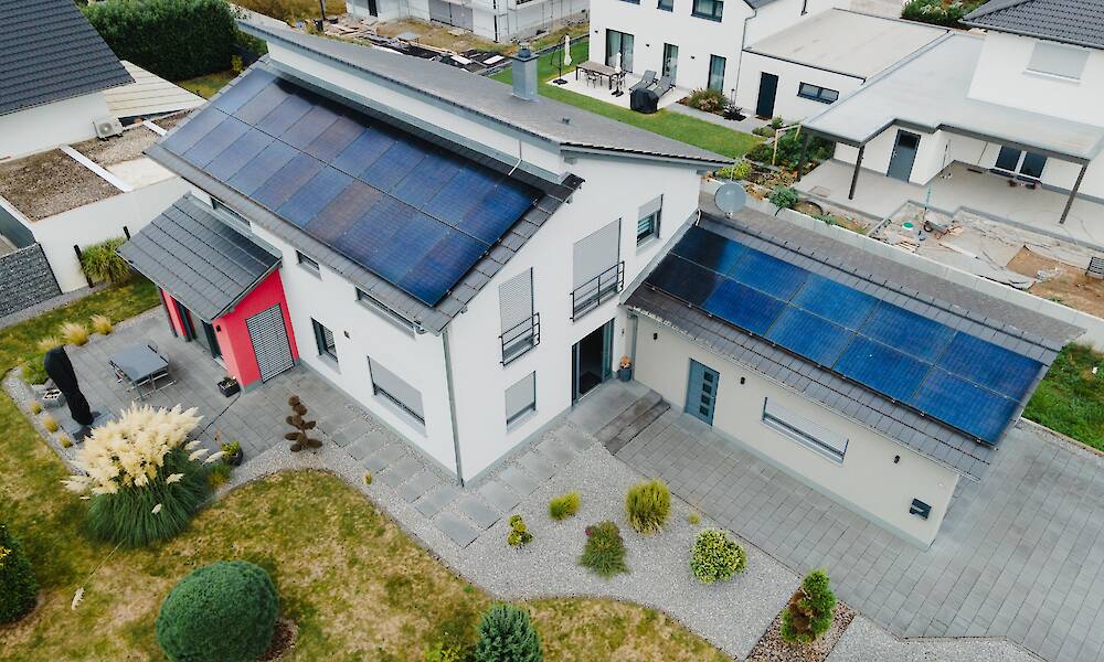 Ein modernes Wohngebiet mit Häusern, von denen einige große Solaranlagen auf den Dächern haben.